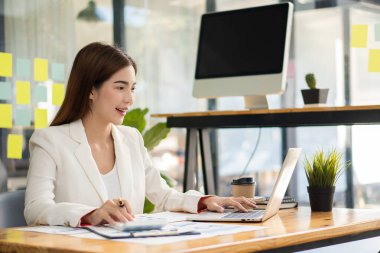 Ofiste dizüstü bilgisayarında çalışan Asyalı güzel bir kadın. Finansal istatistik veri analizi grafiği büyüyen iş dünyası fikrine bakan iş kadını