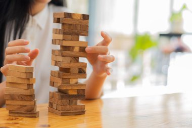 Kadın eli, mahkeme taktikleri ve taktikleri uygulamak için dengesiz Jenga bloklarından tahta blokları yavaş yavaş çeker. Stratejik Düşünme ve Risk
