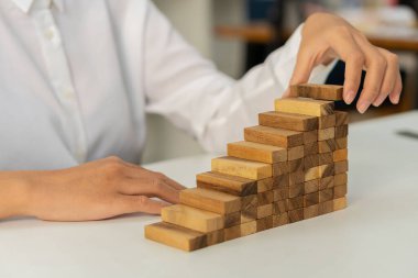 Bir kadının eli merdivenlere tahta bir blok koyar ve başarılı bir iş geliştirme fikrine doğru yol alır..