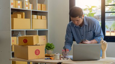 Girişimciler Küçük İşletme Bağımsız Adamlar evde çalışıyor. Ticari denetim, çevrimiçi pazarlama, paketleme, KOBİ satıcıları, konsept, e-ticaret ekibi, çevrimiçi satış için akıllı telefon ve dizüstü bilgisayar kullanın.