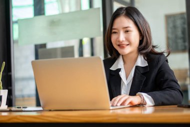 Asyalı iş kadını, kahve dükkanlarındaki müşterilerle dizüstü bilgisayar ve internet iletişimini kullanıyor. Laptopta oturan çekici kadın ve meşrubat restoranında akıllı telefon.