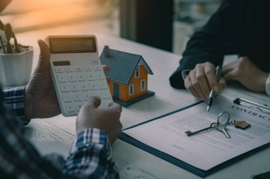 Satış temsilcileri, emlak acentelerinde sözleşme imzalamak için ev taksitleri ve ev alımları için faiz oranı sözleşmeleri sunuyor. mortgage konsept ev satın alma sözleşmesi