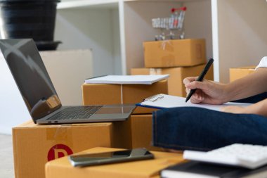 Küçük Girişimci, Girişim, KOBİ, Çalışmak için Genç Asyalılar ve Sevkiyat Konteynerleri çevrimiçi pazar yeri KOBİ 'si e-ticaret fikirlerini paketlediler ve evdeki dizüstü bilgisayarda müşteri siparişlerini kontrol ettiler.