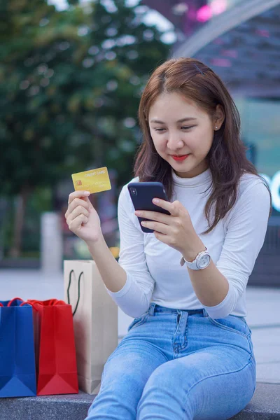 亚洲妇女使用信用卡在网上购物和购买手机 及膝上型电脑网上购物电子商贸付款交易汇款技术 — 图库照片
