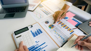 Şirketin büyüme planlarının başarısını tartışmak üzere toplanan finans yöneticilerinin üst düzey görüşü. Grafikler, defterler ve dijital tabletlerle stratejik başlangıç projesi finansal istatistikleri.