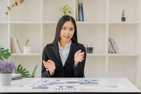 Asian businesswoman sitting at a desk young woman working data analysis charts financial documents with laptop in the office