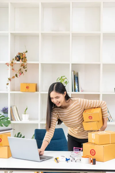 Küçük işletme girişimi KOBİ işletme sahipleri dizüstü bilgisayarı kullanarak kutu hazırlamak ve çevrimiçi siparişleri kontrol ediyorlar. Müşterilere satıyorum. Çevrimiçi KOBİ iş fikri.