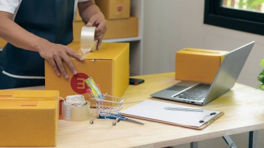 Asyalılar dizüstü bilgisayarlarla çalışıp online numaraları kontrol ediyorlar, şirket kuruyorlar, küçük işletme sahipleri, e-ticaret konseptleri, genç kadınlar eşyaları kutulara koyup müşterilere yolluyorlar..