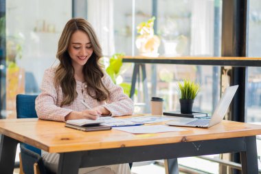 Bir iş analisti ya da muhasebeci mali belgeleri hesaplar ve inceler. Asyalı iş kadını dizüstü bilgisayarla tasarruf, finans ve ekonomi kavramını hesaplıyor.