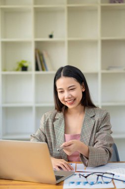 Bir iş analisti ya da muhasebeci mali belgeleri hesaplar ve inceler. Asyalı iş kadını dizüstü bilgisayarla tasarruf, finans ve ekonomi kavramını hesaplıyor.