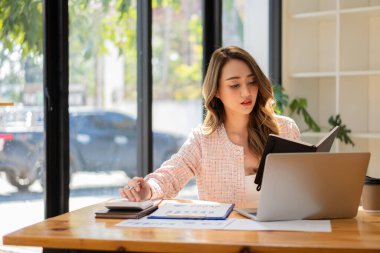 Bir iş analisti ya da muhasebeci mali belgeleri hesaplar ve inceler. Asyalı iş kadını dizüstü bilgisayarla tasarruf, finans ve ekonomi kavramını hesaplıyor.