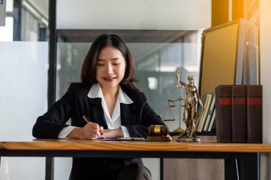 Avukatlık bürosu. Adalet Tanrıçası, kanunlar, tavsiyeler ve adalet üzerine çalışan avukatlar. Çekiç ve femida ile çalışan kadın avukat.