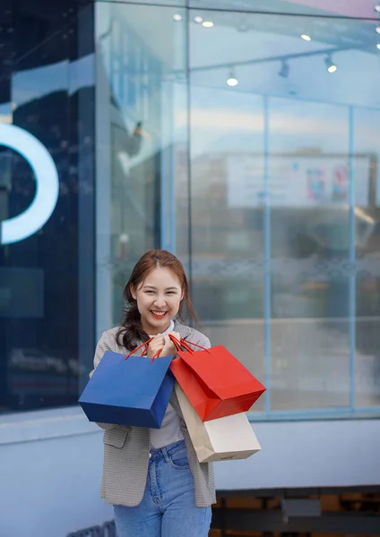 一个年轻的女人把购物袋放在百货商店前面 高兴地挑选她最喜欢的东西 — 图库照片