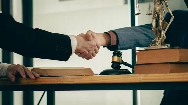 Male lawyer with client shaking hands in the office Businessmen shake hands to seal a deal with a partner lawyer or a lawyer who discusses a contract agreement.