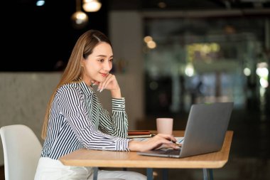 Muhasebecilik yapan genç Asyalı iş kadını Finans Grafiği ev ödevi videosu çekerken yurtdışını arıyor. İnternet bağlantısı olan iş kadını finansal verileri analiz etmek için bilgisayar kullanıyor.