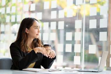 Muhasebecilik yapan genç Asyalı iş kadını Finans Grafiği ev ödevi videosu çekerken yurtdışını arıyor. İnternet bağlantısı olan iş kadını finansal verileri analiz etmek için bilgisayar kullanıyor.