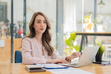 Muhasebecilik yapan genç Asyalı iş kadını Finans Grafiği ev ödevi videosu çekerken yurtdışını arıyor. İnternet bağlantısı olan iş kadını finansal verileri analiz etmek için bilgisayar kullanıyor.