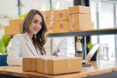 İş yerinde kutu ve dizüstü bilgisayarla çalışan Asyalı bir kadın, küçük işletme sahibi Girişimcilik, küçük işletme, KOBİ veya serbest internet üzerinden ve dağıtım fikirleri başlatıyor.