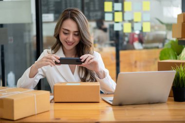 İş yerinde kutu ve dizüstü bilgisayarla çalışan Asyalı bir kadın, küçük işletme sahibi Girişimcilik, küçük işletme, KOBİ veya serbest internet üzerinden ve dağıtım fikirleri başlatıyor.