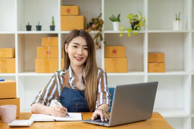 İş yerinde kutularla çalışan Asyalı bir KOBİ kadınının portresi. Küçük işletme sahipleri, KOBİ veya serbest çalışanlar ve başarılı çevrimiçi pazar dağıtım kutusu fikirleri başlat.