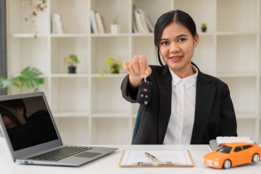 Araba satıcısı masanın anahtarlarını uzattı. Satma, kiralama ve araba sigortası kavramı. Düz ögeler, minyatür araba modelleri, kopya alanı ve maketi olan örnek sözleşmeler ve kalemler.