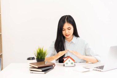 Evin model masasındaki evi koruyan genç bir kadın. sigorta kavramı