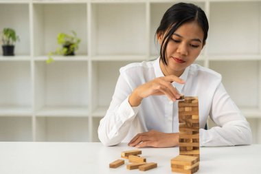 Riskler ve stratejiler, planlama, elle kumar. Kuleye tahta bloklar yerleştirmek Sopalar Piramidi İnşa etmek Ofisteki Eğlence Geleceği Planlayan Kız 'ın başarıya inandığını gösterir.
