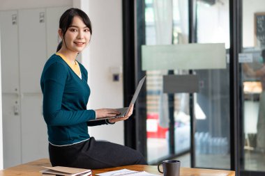 Asyalı kadınlar masadaki dizüstü bilgisayarlar, bilgisayarlar ve kaplan derileriyle çalışırlar. Küçük işletme sahipleri, çalışanlar, çevrimiçi, serbest, KOBİ pazarlama, e-Ticaret, finans, ofis pazarlama fikirleri.