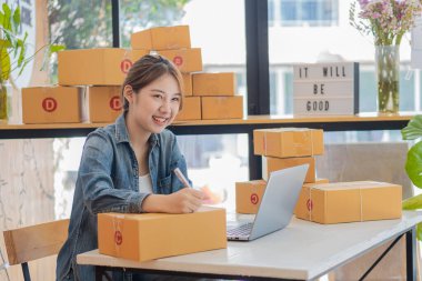 Genç İş Sahipleri Ev Sahipleri Çevrimiçi İş Fikirleri Girişimcilik Küçük İş KOBİ, kargo ürünlerine kutu hazırlamak için dizüstü bilgisayarlar kullanır ve kontrol eder. Satışlar