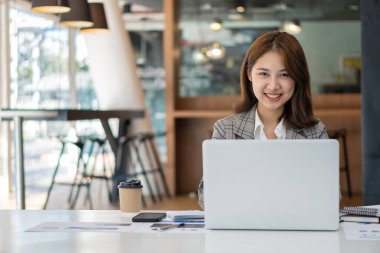 Güzel Asyalı iş kadını hesap makinesi kullanarak analiz çizelgesi, ofiste elinde kağıtlar ve elinde kalemle modern ev stüdyosundaki sandalyede oturuyor. Cep telefonu işçisi müşterilerle bağlantı kuruyor