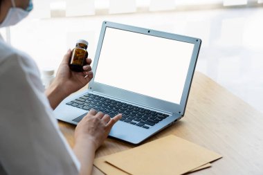 Doktor elinde ilaç şişesi ve dizüstü bilgisayarda klavye tutuyor. Tıp bürosunda reçete yazan bir doktor ya da hemşirenin eli. Sağlık ve sağlık kontrolü kavramı