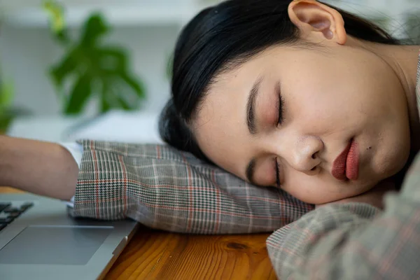 Çekici Asyalı iş kadını uyuyor, uykulu ya da masasında gündüz uyukluyor. Ofisteki mali dosyalardan bıkmış bir muhasebeci. Finansal tablo ve dizüstü bilgisayar masada.