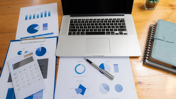 İş finans bürosu konsepti, iş adamı masasının üstünde dizüstü bilgisayarı ve grafik dokümanları. Hesap makinesi ve ekipman kopyalama alanı ile düz yatar.