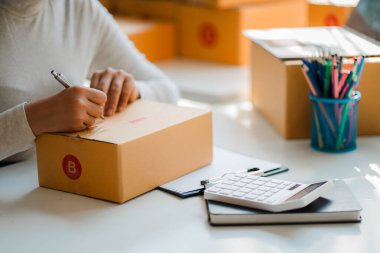 Küçük girişimciler ürünlerini sarı paket kutulara yerleştirerek KOBİ işlerini evde başlatıyorlar. Fikir, sipariş almak ve sevkiyat yapmak için dizüstü bilgisayarlarla internet üzerinden satış yapmaya başlamak..