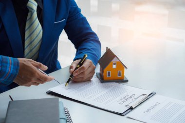 Emlak büroları müşterilerine masalarında ev satış sözleşmeleri sunar.