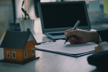 Emlak büroları müşterilerine masalarında ev satış sözleşmeleri sunar.
