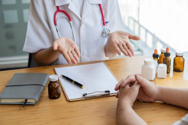 Kadın bir doktor hastaya, ilaç ve tıbbi konseptler hakkında bilgi verirken ilaç geçmişi olan bir dosya formu doldurmalarını ister..