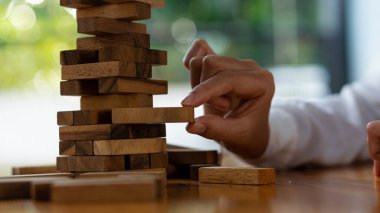 Kızın eli, kuleyi devirmeden tahta bloğu sökmeye çalıştı. Yetenek grubu oyunu İnşaat işi risk konsepti. Yanındaki metin için yeri olan yakın plan fotoğraf.