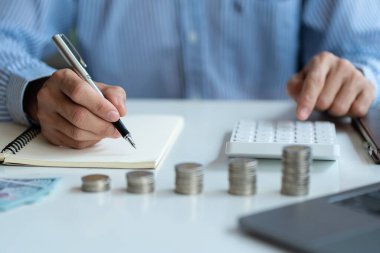 Muhasebeci, kazancı ve para yığınını hesaplamak için hesap makinesine basar..