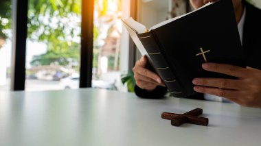 İncil 'i tutan Hristiyan kadın kadın eline hafifçe odaklan. Hıristiyanlık 'tan af ve iyilik için dua ederken arka planda bulanıklık vardı..