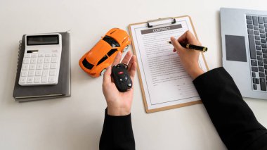 Satıcı bir kalem tutar, kirayı gösterir ve müşteriye araba ticareti ya da araba kredisi imzalaması için arabanın anahtarlarını verir ya da ofis masasındaki kiralık araba sigortasını..