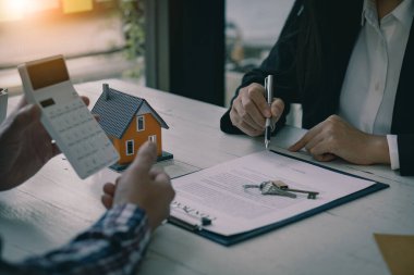 Satış temsilcisi bir ev satın alma sözleşmesi sunar ve projeyi yeni ev sahibinin müşterileri çalışma masasında satın alma ya da kiralama sözleşmesini imzaladıklarında onlara yakın olarak sunar..