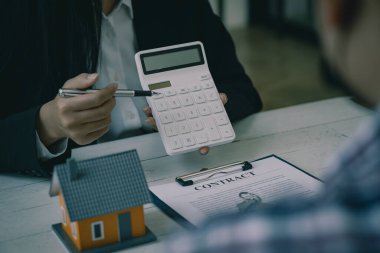 Satış temsilcisi bir ev satın alma sözleşmesi sunar ve projeyi yeni ev sahibinin müşterileri çalışma masasında satın alma ya da kiralama sözleşmesini imzaladıklarında onlara yakın olarak sunar..