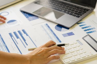 İş adamının elleri hesap makinesine basıyor, hesaplıyor, analiz ediyor, grafikliyor, çiziyor, muhasebe işçisi dizüstü bilgisayarda çalışıyor. Finansal raporlar ya da şirket karları hakkında danışmanlık yapan bir banka memuru.