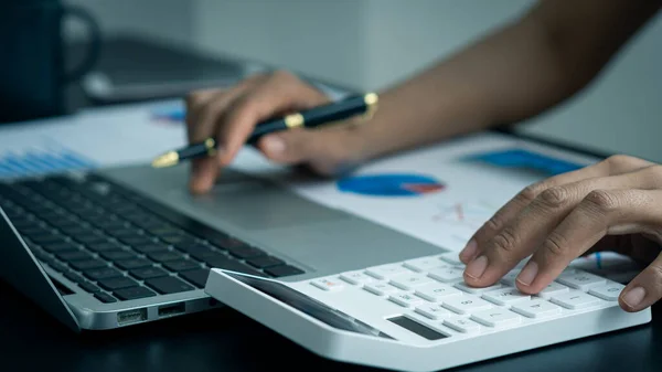 Businessman\'s hands pressing a calculator, calculating, analyzing, graphing, charting, accounting worker working on a laptop. A bank clerk who advises making financial reports or company profits.