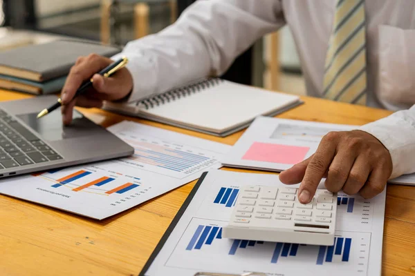 İş adamının elleri hesap makinesine basıyor, hesaplıyor, analiz ediyor, grafikliyor, çiziyor, muhasebe işçisi dizüstü bilgisayarda çalışıyor. Finansal raporlar ya da şirket karları hakkında danışmanlık yapan bir banka memuru.