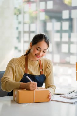 Bir KOBİ iş fikri başlatın, girişimci, genç Asyalı kadın, evden çalışan küçük işletme. Paketleme ve Nakliye serbest konsepti Dizüstü bilgisayarlarda çevrimiçi alışveriş 