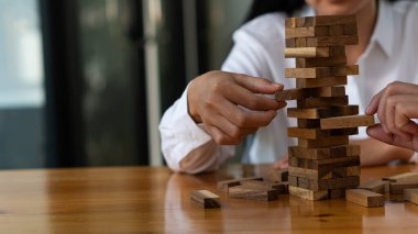 Asyalı iş kadınının el kulesi ofiste tahta blokları olan bir kule inşa ediyor, oyunlar oynuyor, masasında oturuyor. Geleceğin çalışanlarını planla bir proje ya da iş stratejisi geliştir, karar ver