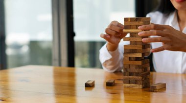 Asyalı iş kadınının el kulesi ofiste tahta blokları olan bir kule inşa ediyor, oyunlar oynuyor, masasında oturuyor. Geleceğin çalışanlarını planla bir proje ya da iş stratejisi geliştir, karar ver
