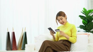 Asyalı kadınlar kredi kartlarını dijital mobil cihazlar kullanarak ve online alışveriş yaparak, akıllı telefonlara banka kartı numaralarını yazarak ve mobil bankacılık uygulamaları kullanarak işleterek tutuyorlar. çevrimiçi alışveriş kavramı